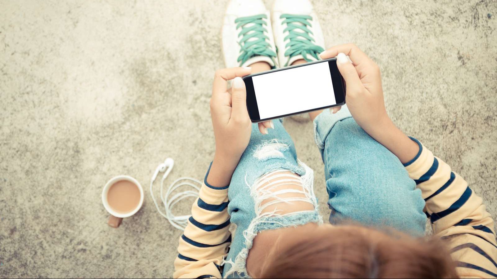 Pige sidder med sin telefon