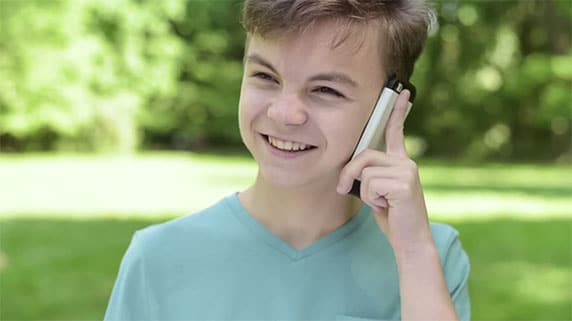 Smilende dreng taler i telefon
