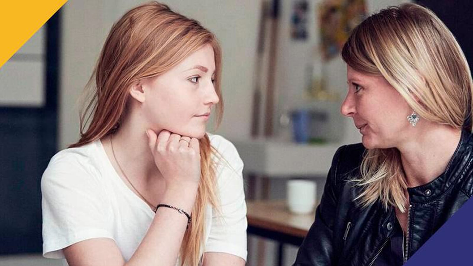 En rådhåret pige og en lyshåret dame kigger hinanden i øjnene.