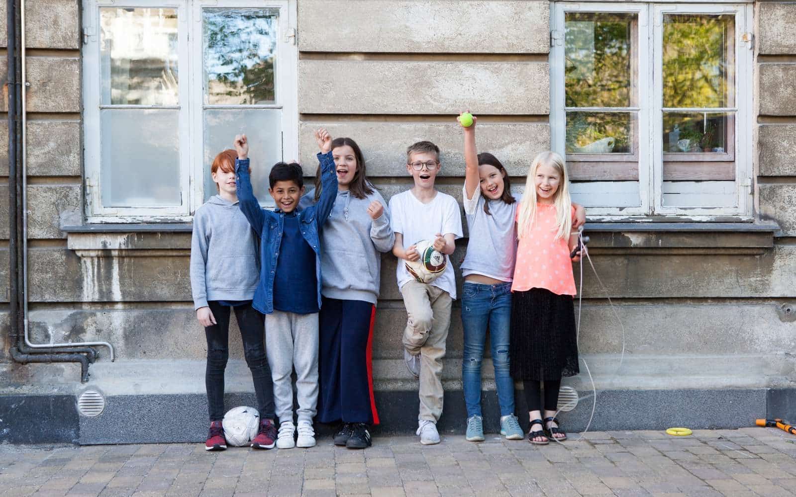 En gruppe børn står op af en mur