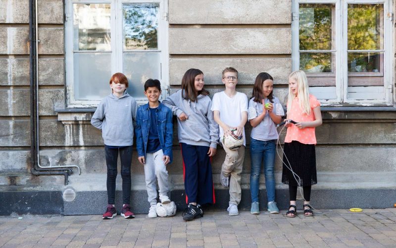 En gruppe børn står op ad en mur