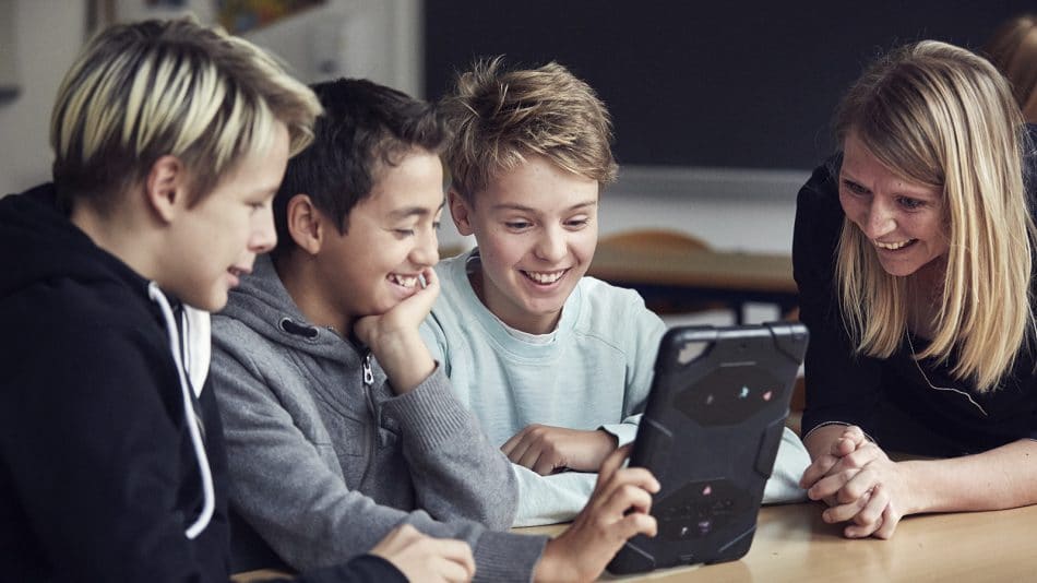 Tre drenge og en skolelærer kigger på iPad