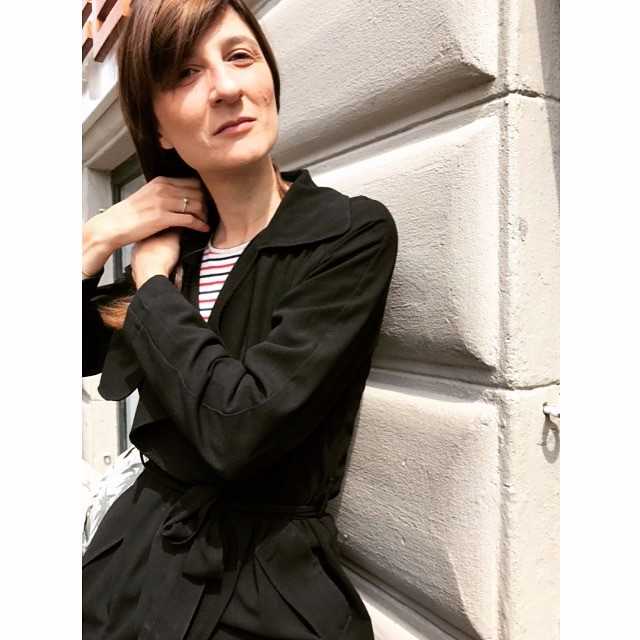 Mørkhåret kvinde i sort jakke holder om sit hår