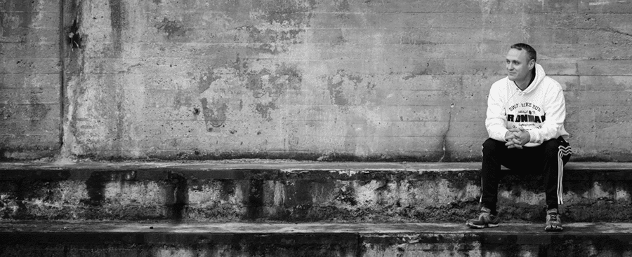 Sort-hvidt billede af mand der sidder op ad en mur