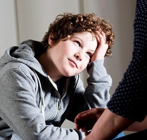 Dreng med krøller kigger op og tager sig til hovedet