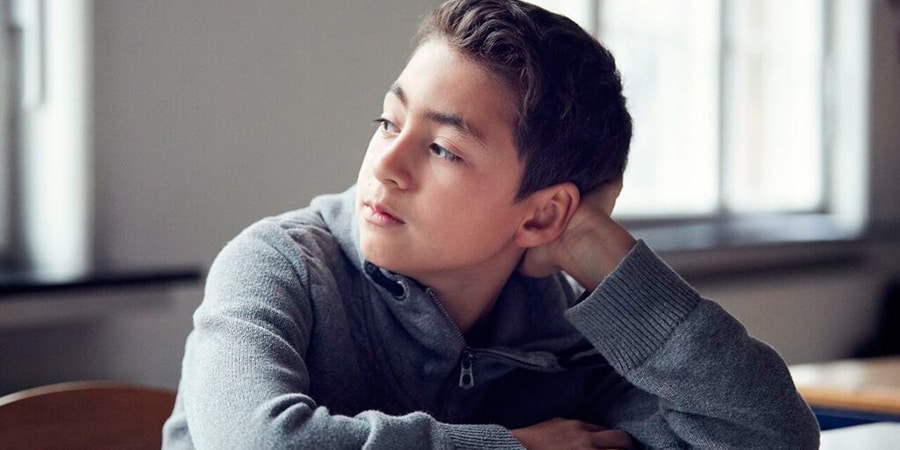 Mørkhåret dreng læner sig op af sin hånd og kigger ud til venstre