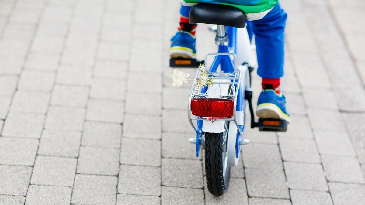 Barnecykel med en blomst bagpå der bliver cyklet