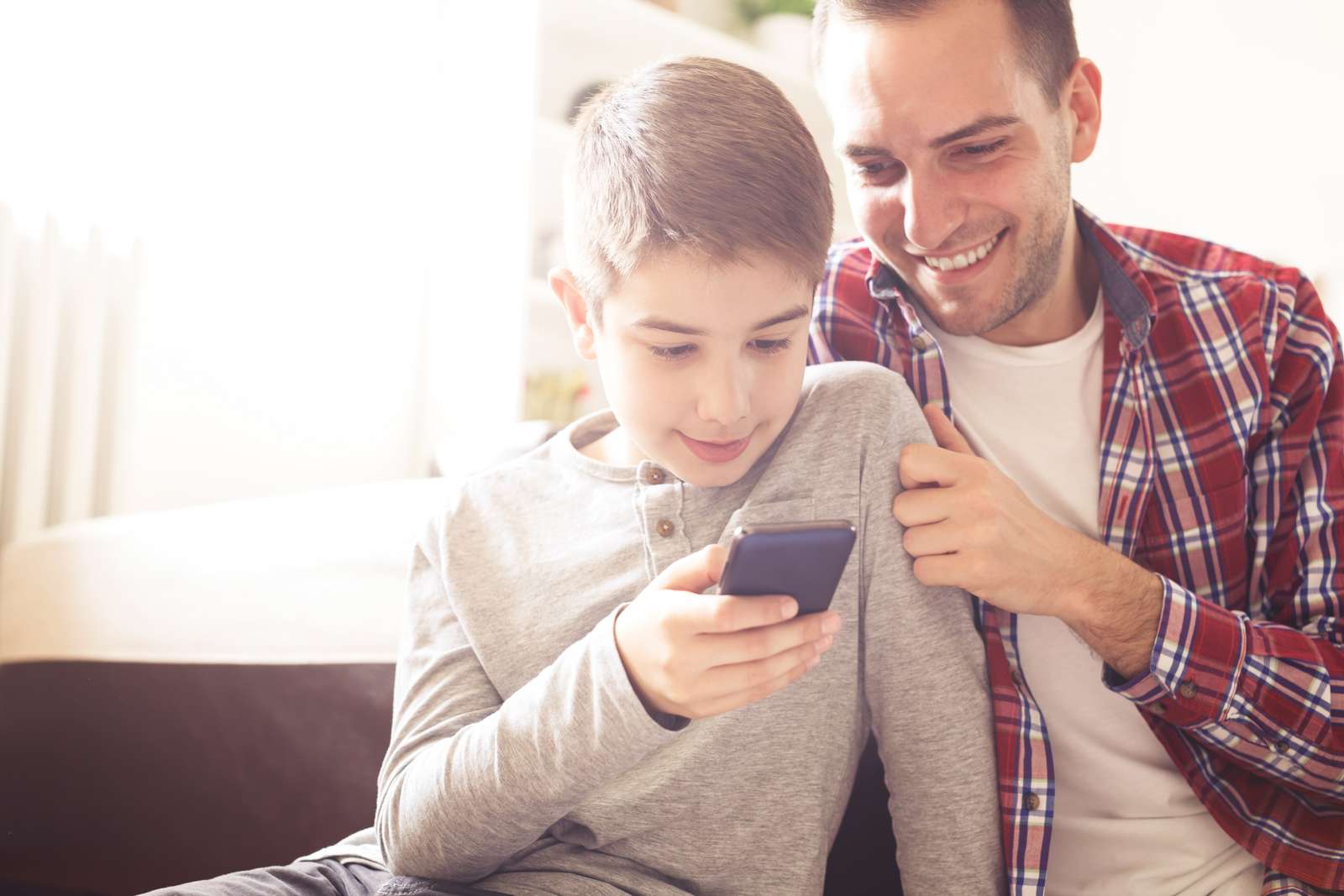 Far og barn sidder og kigger på en mobiltelefon