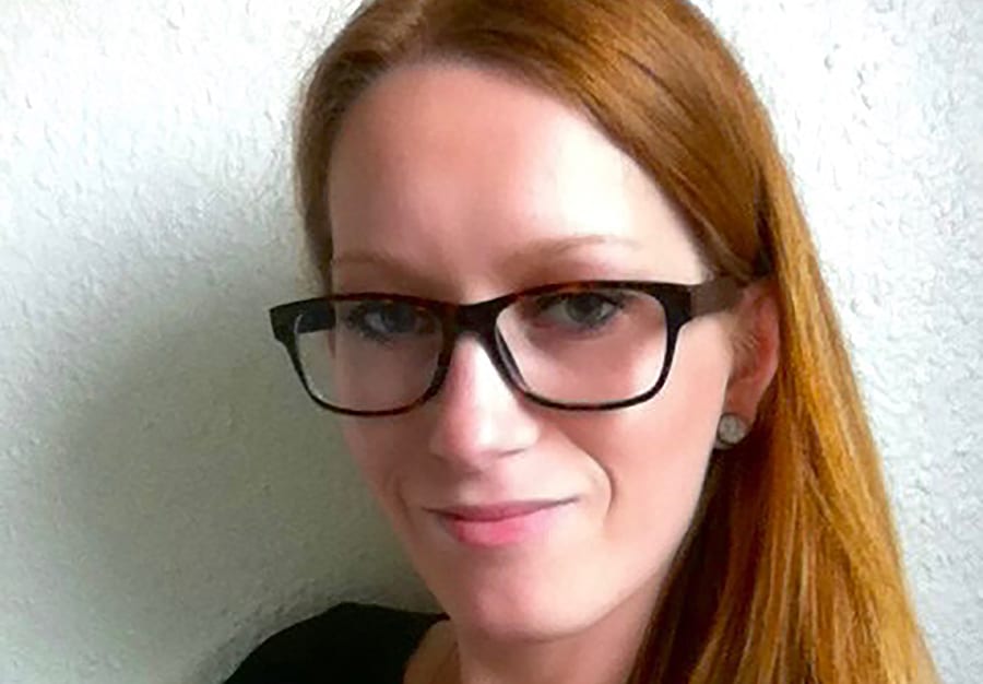 Rødhåret kvinde med briller kigger ind i kameraet