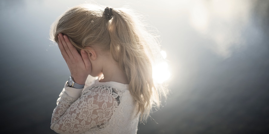 Lyshåret pige holder sig for ansigtet