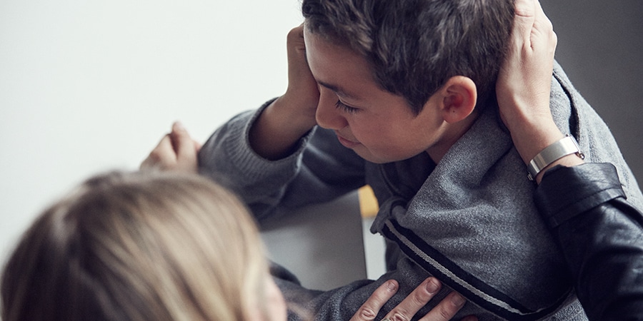 Kvinde holder om hovedet på en grædende dreng