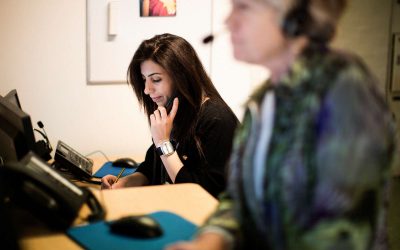 Mørkhåret kvinde fra BørneTelefonen sidder og snakker i telefon med et barn