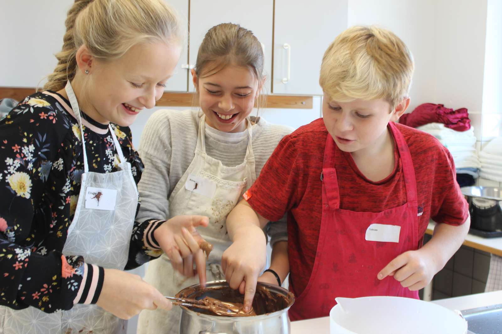 Tre børn står og smelter chokolade