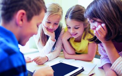 Fire skolebørn sidder og kigger på en iPad