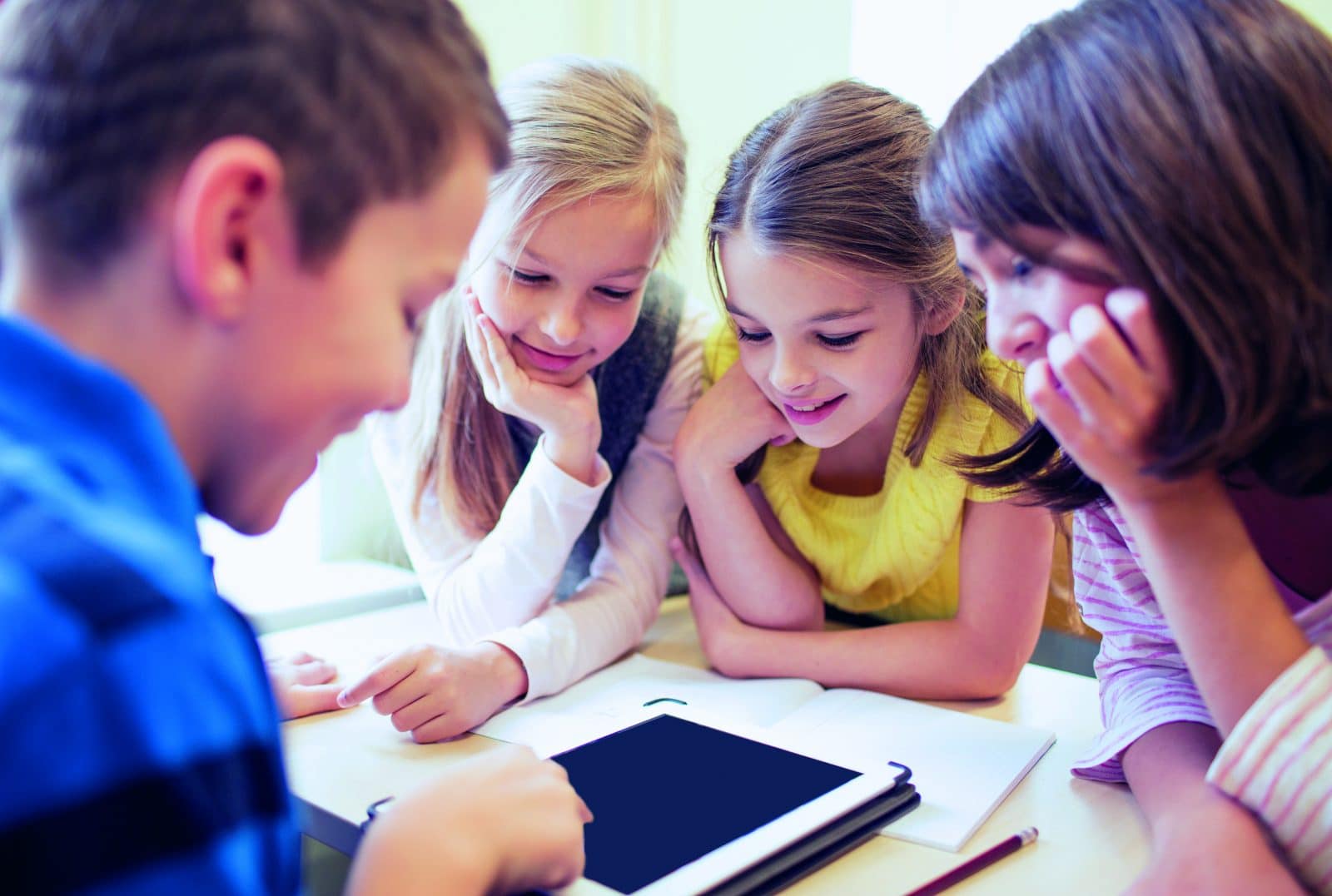 Fire skolebørn sidder og kigger på en iPad