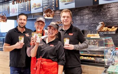 Fire arbejdere fra Circle K holder børnekaffe i hænderne og smiler til kameraet