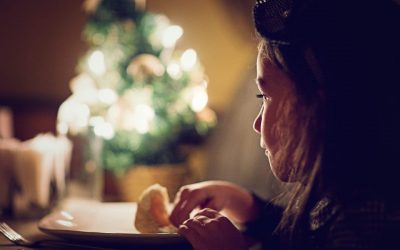 Pige set i profil sidder foran en tallerken, med et sløret juletre i baggrunden