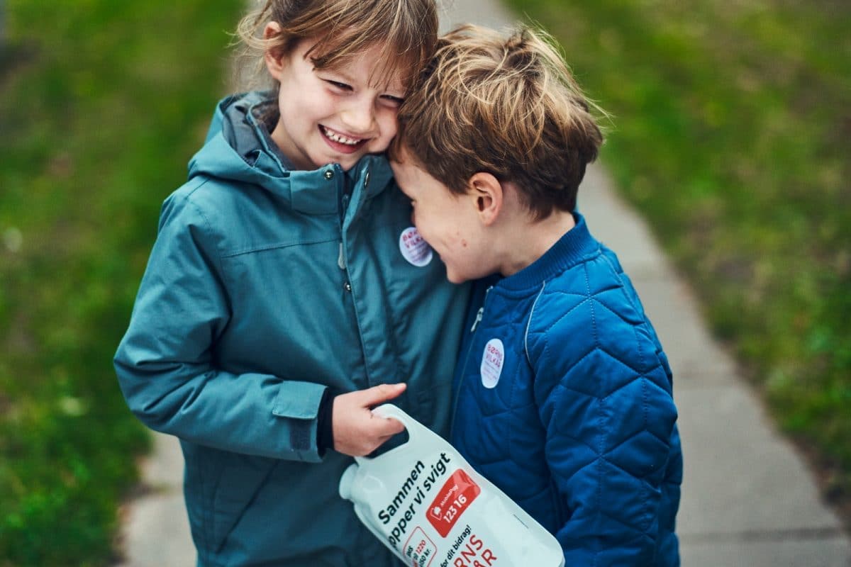 Dreng og pige med indsamlingsbøtte i hånden, krammer