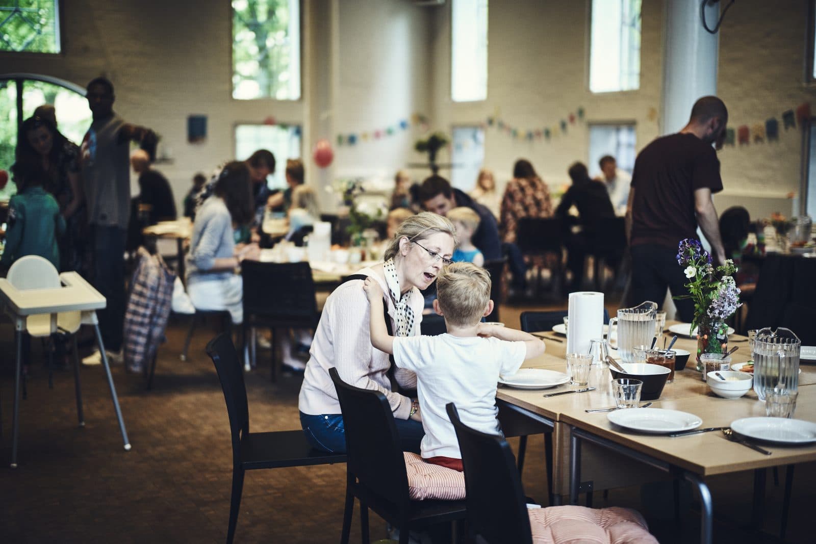 Kvinde og barn sidder ved et bord i en sal