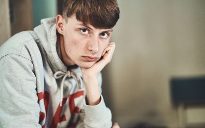 Mørkhåret dreng læner hovedet op ad hånden og kigger ind i kameraet