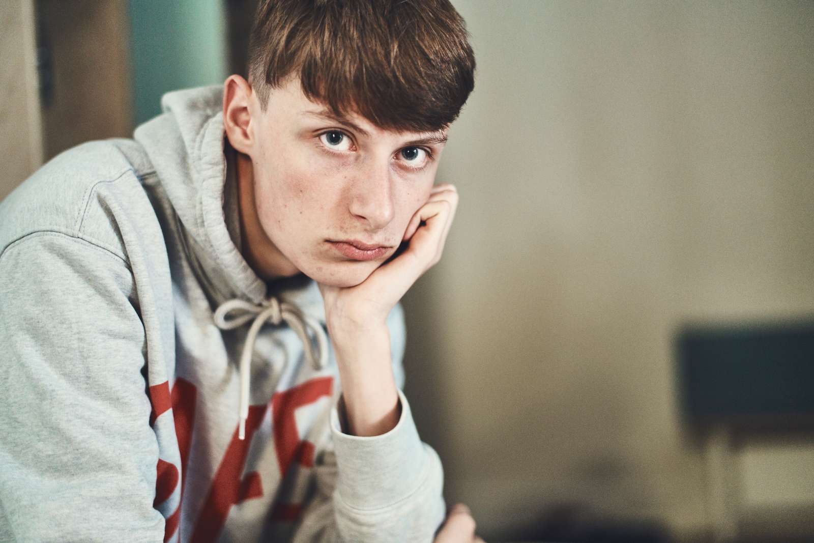 Mørkhåret dreng læner hovedet op ad hånden og kigger ind i kameraet