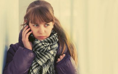 Brunhåret pige står op ad en væg og taler i telefon