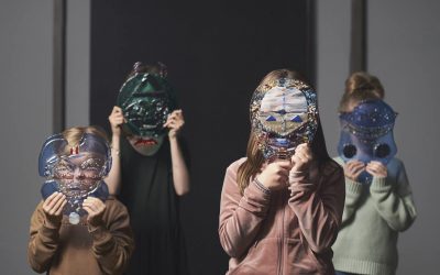 Fire børn står med masker holdt foran ansigtet