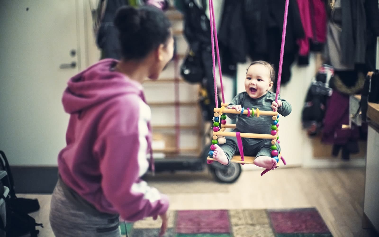Mørkhåret baby smiler til mørkhåret kvinde.