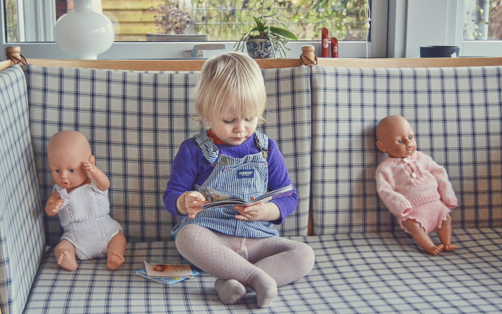 Lyshåret pige kigger i en bog.