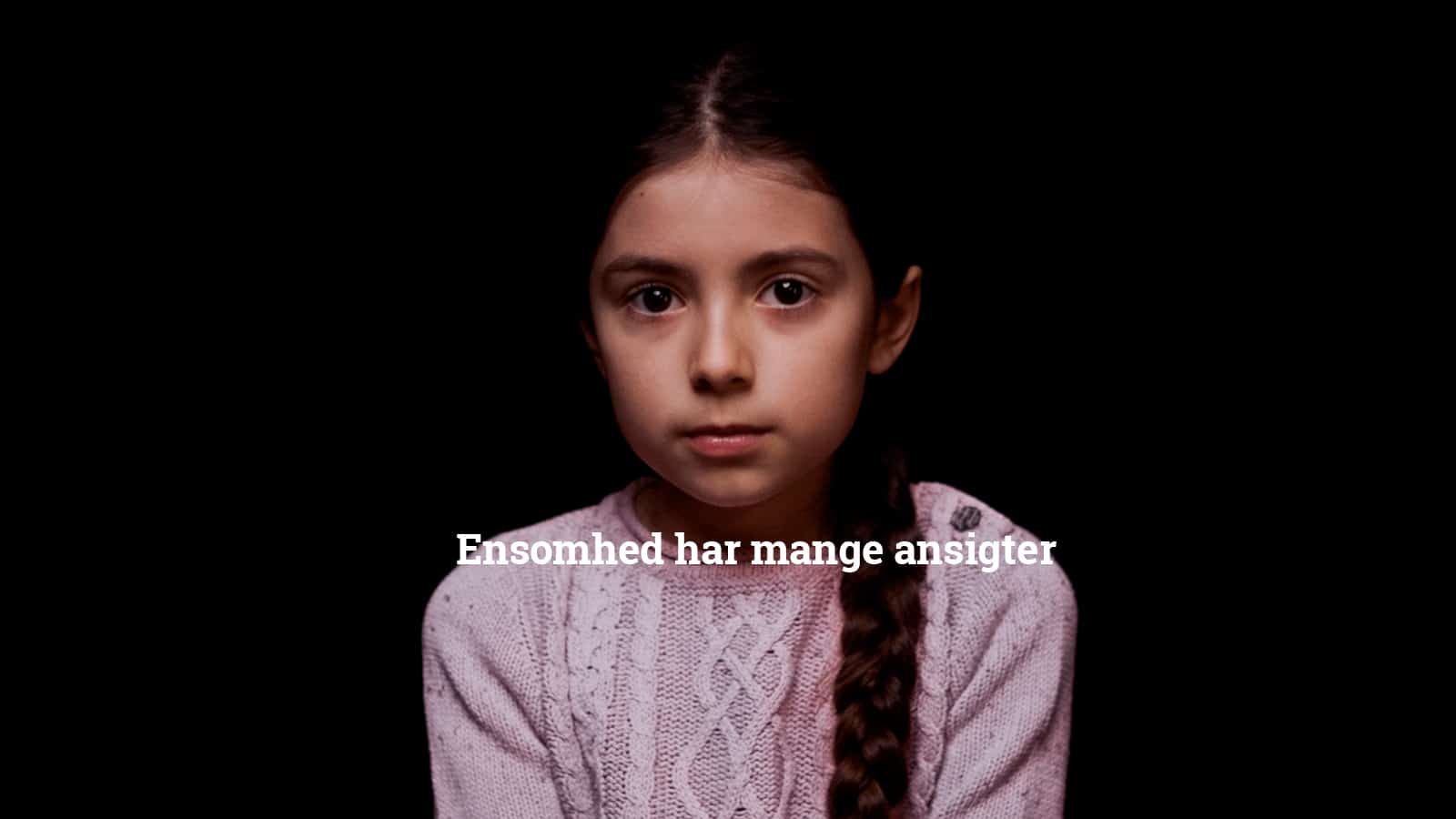 Mørkhåret sidder foran sort baggrund og kigger i kameraet