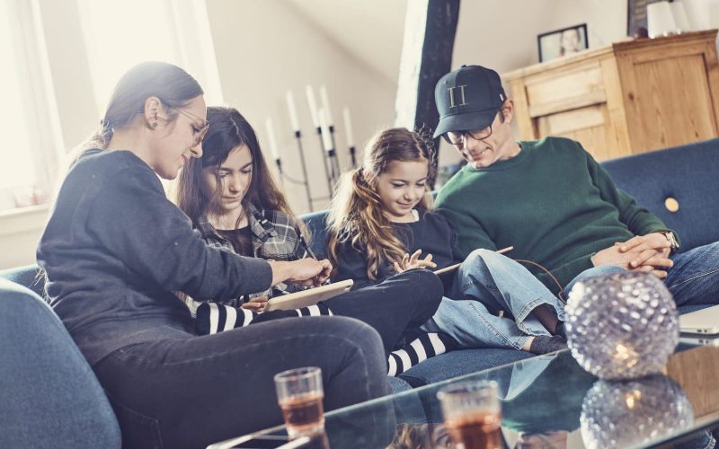 En familie sidder og kigger på to iPads