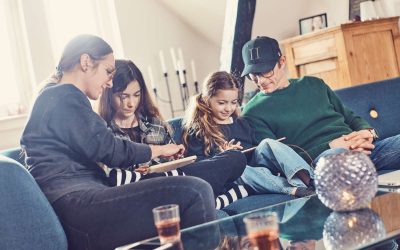 Familie sidder på en sofa og kigger på iPads