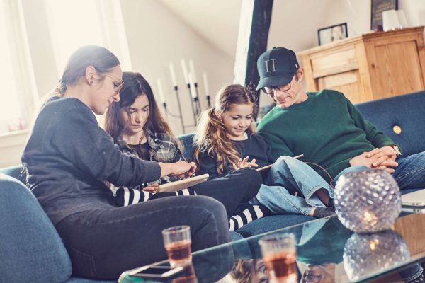 Familie sidder på en sofa og kigger på iPads