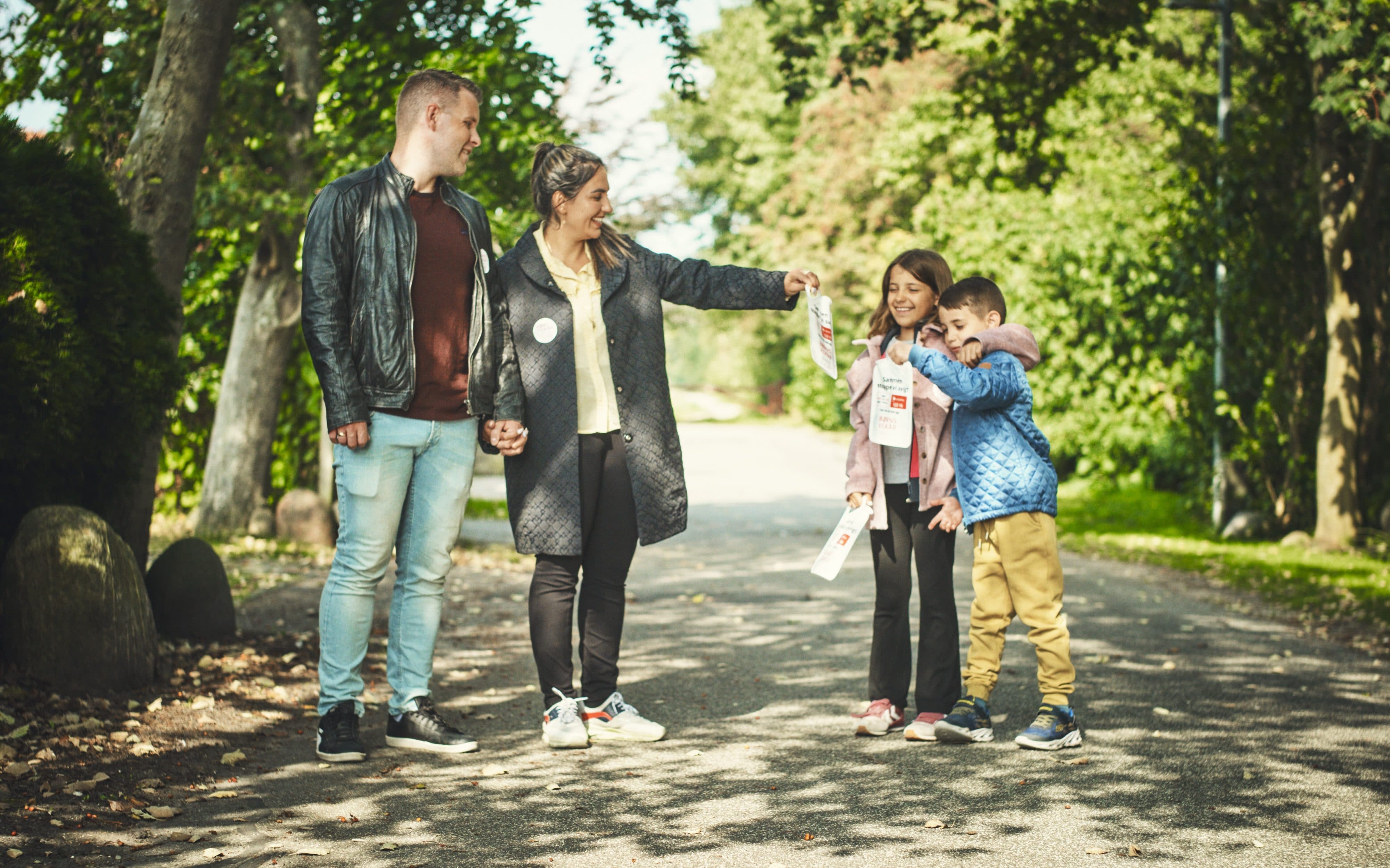 En familie står på en vej med indsamlingsbøtter