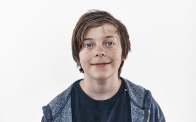 Brunhåret dreng på hvid baggrund kigger i kameraet