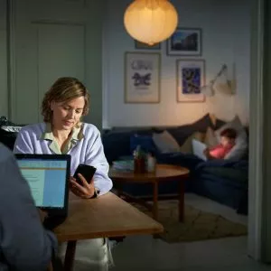 Lyshåret dame kigger på telefon i stue.