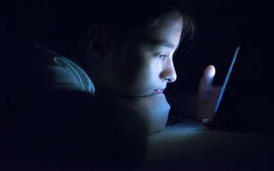 Pige ligger i mørke og kigger på sin telefon
