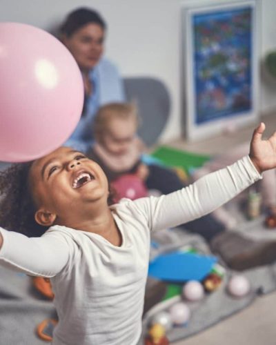 Mørkhåret piger griner stort mens hun leger med en ballon