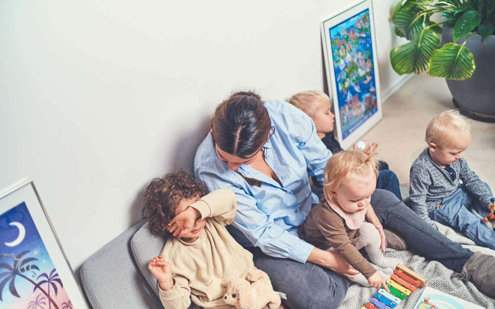 Mørkhåret kvinde set ovenfra sidder med fire børn, mens hun taler med et af dem