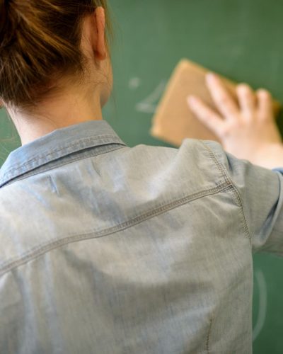 Brunhåret kvinde set bagfra visker ud på en tavle