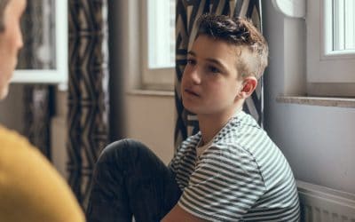Mørkhåret dreng sidder og taler med en voksen