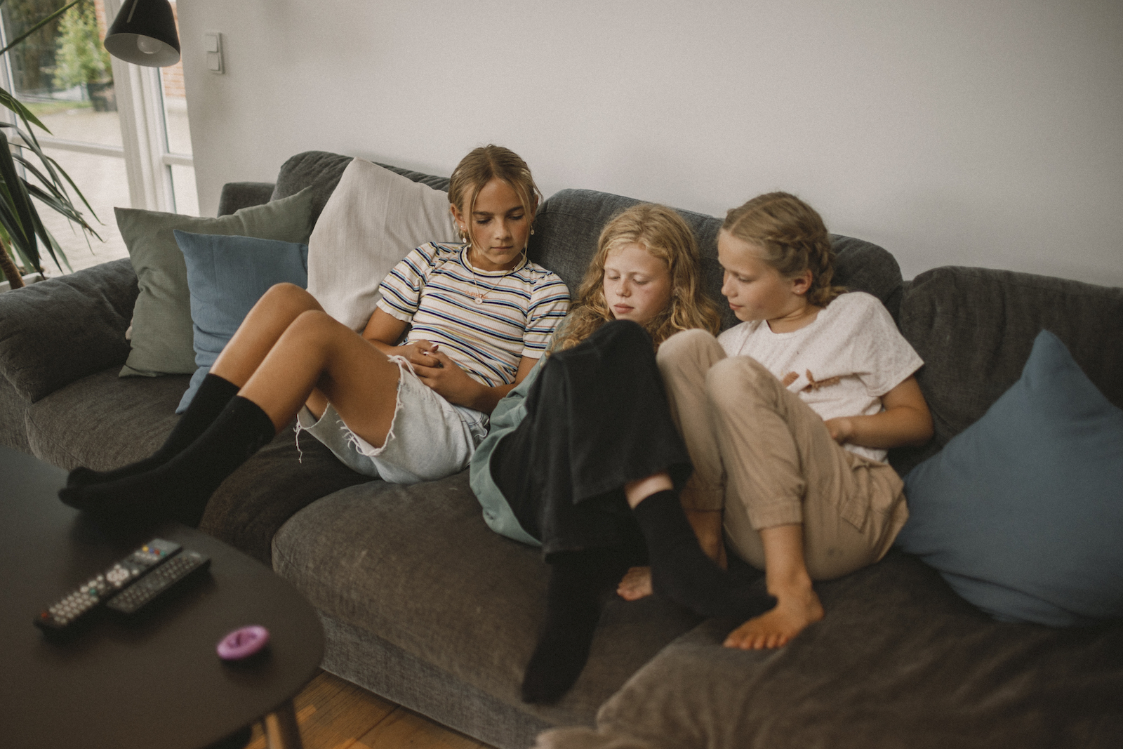 Tre piger på en sofa kigger på en telefon