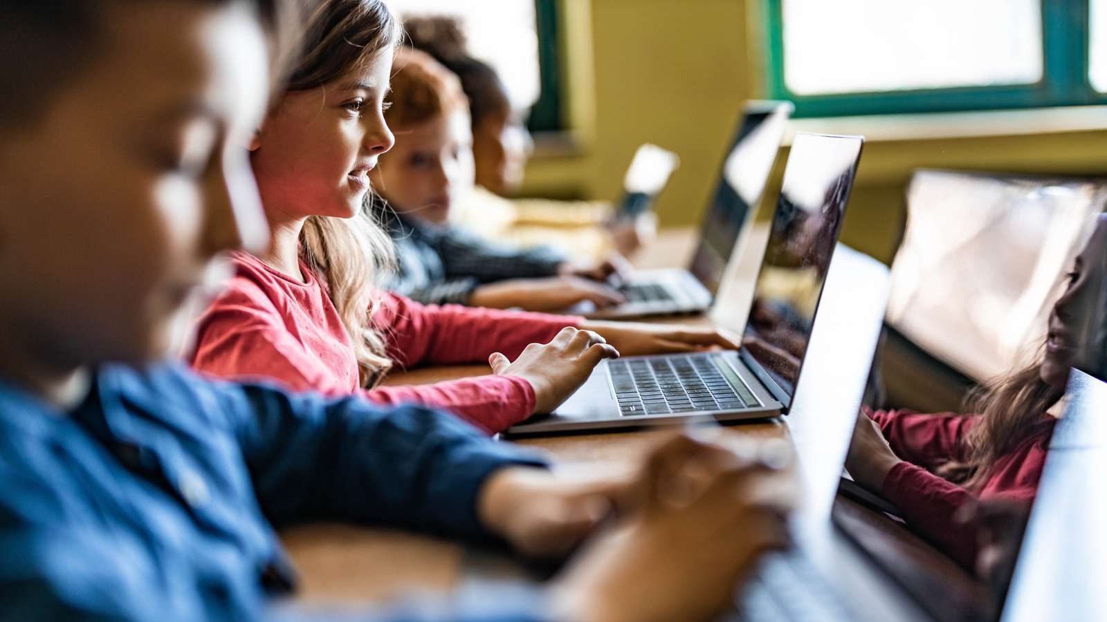 Børn sidder på en række på deres computere