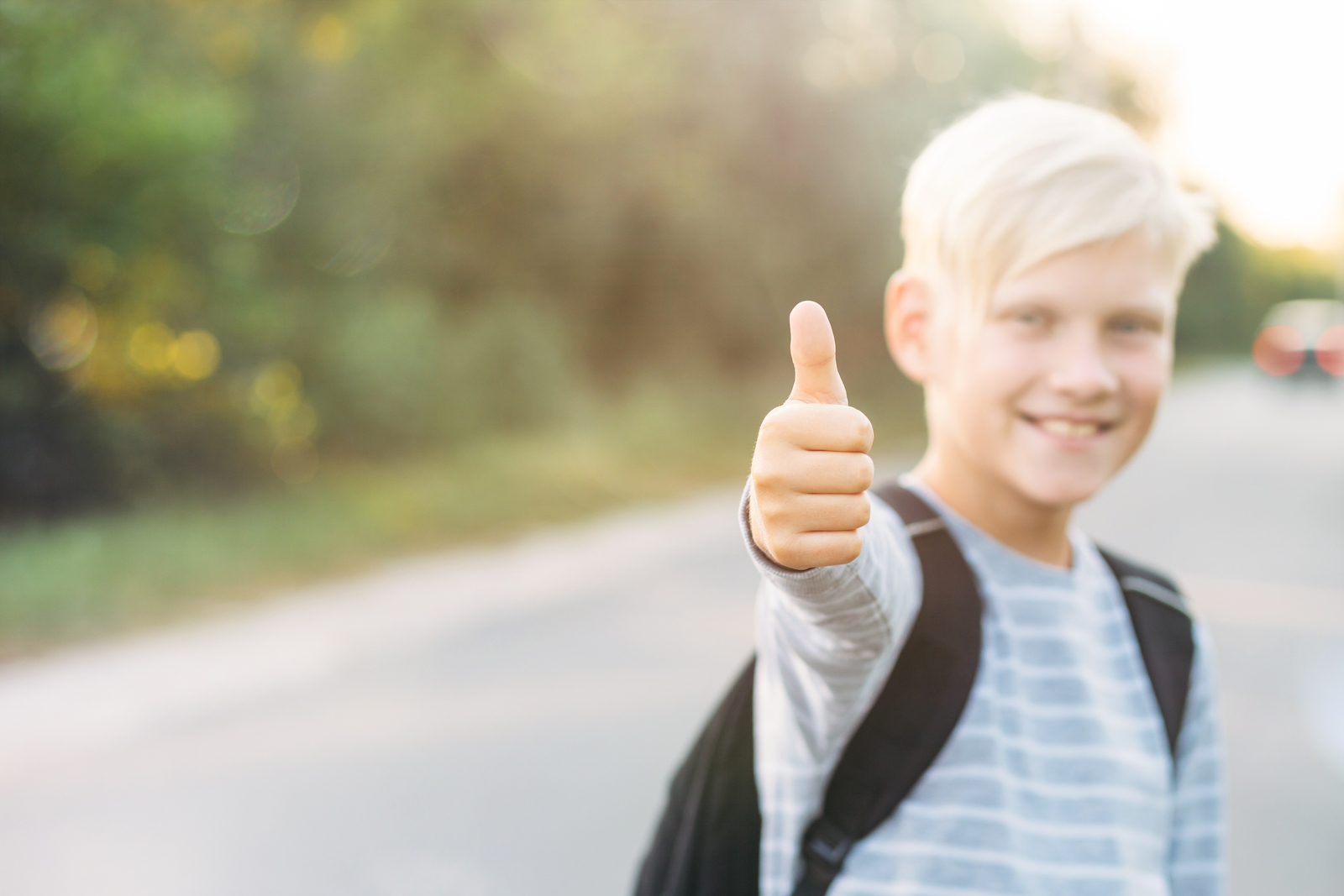 Sløret blond dreng i baggrunden giver tommelfinger op, hvilket er i fokus