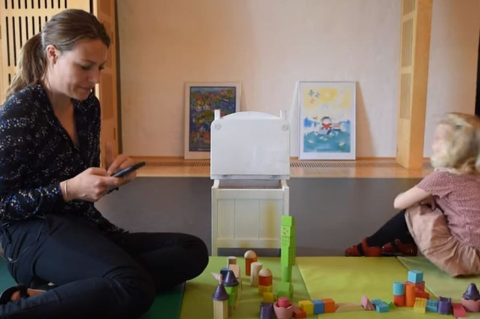 Kvinde sidder på sin telefon med en pige ude til højre