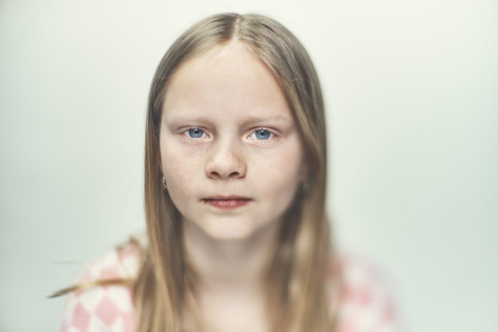 Pige på hvid baggrund kigger ind i kameraet