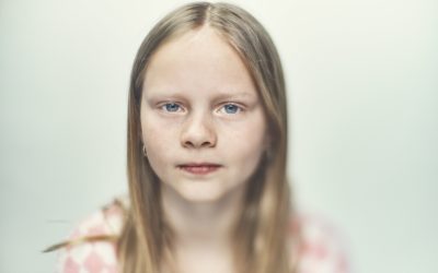 Pige på hvid baggrund kigger ind i kameraet