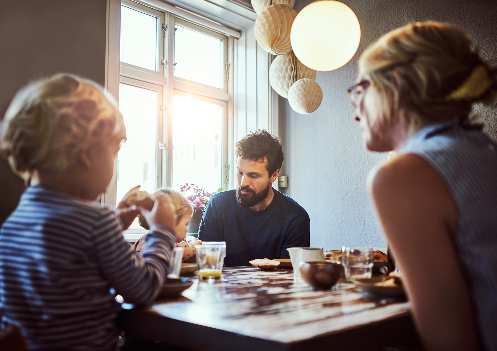 Familie sidder omkring et spisebord og spiser.