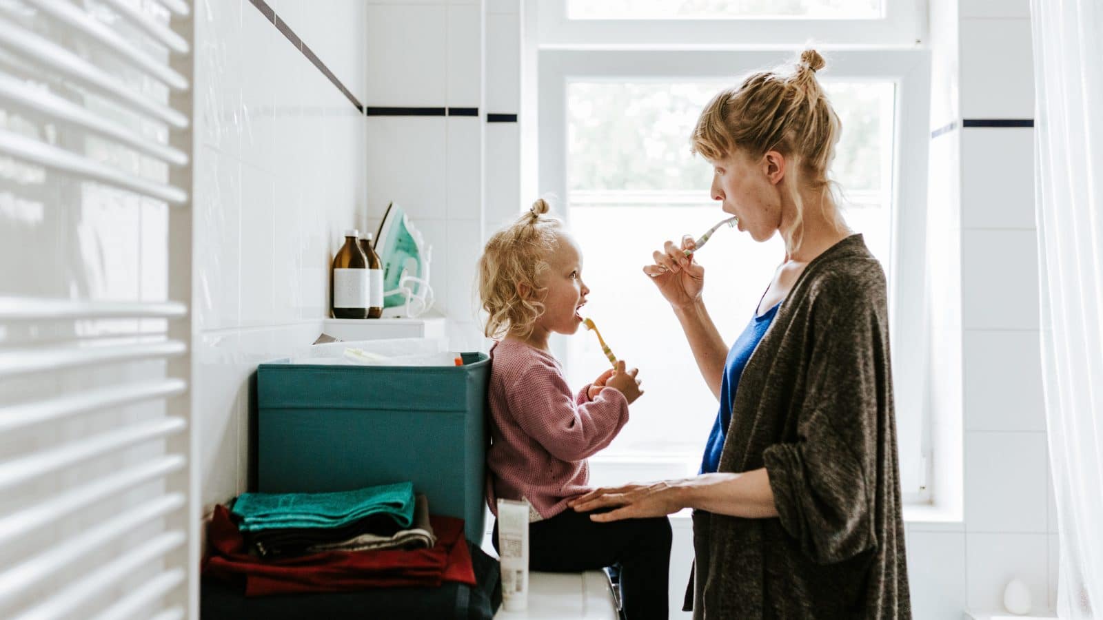 Lyshåret kvinde of lyshåret baby kigger på hinanden mens de børster tænder.