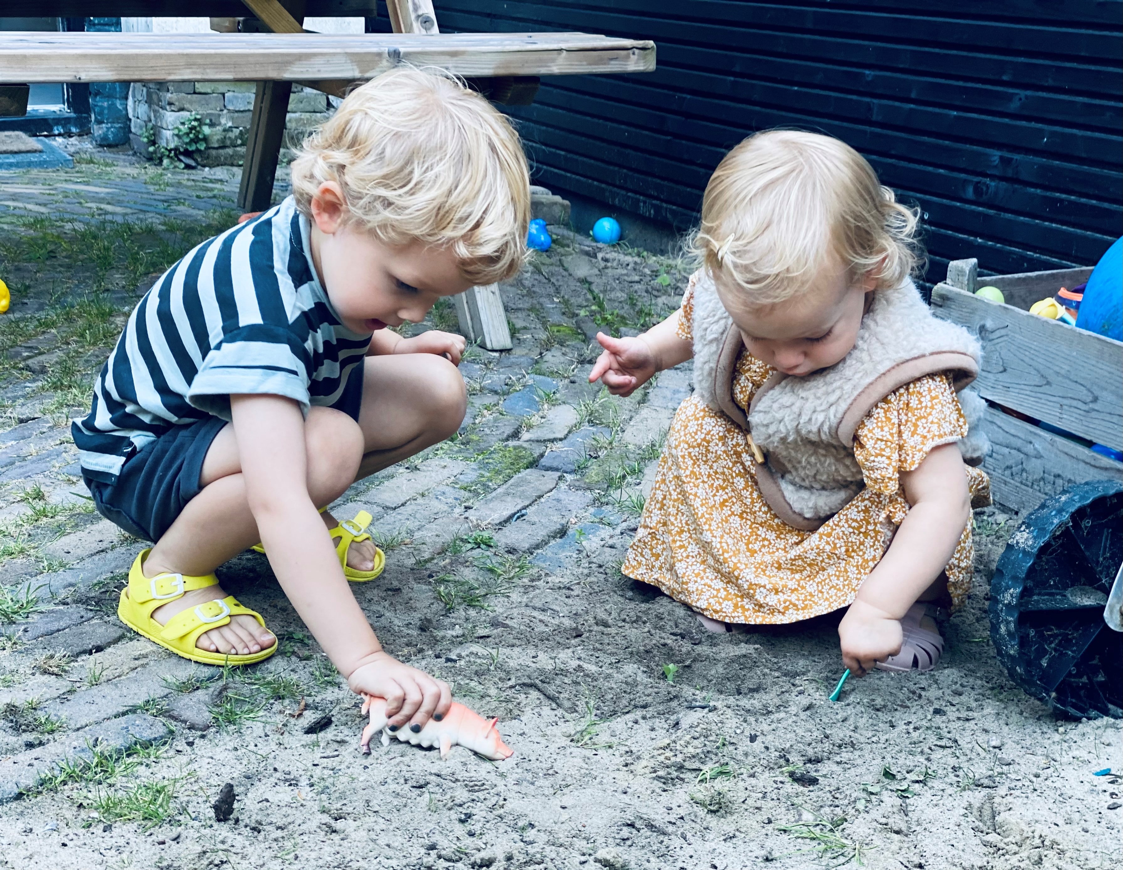 To børn sidder på hug og leger